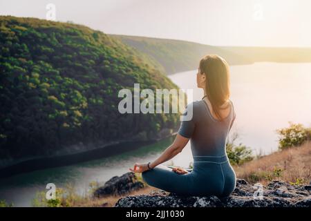 Friedliche Yogi-Frau sitzt im Lotus, meditiert, fühlt sich frei Stockfoto