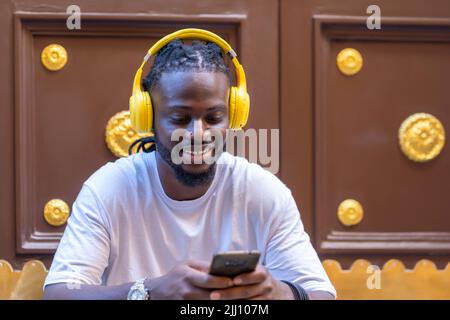 Junger afrikanischer Mann, der ein glückliches Gespräch von seinem Smartphone aus führt Stockfoto