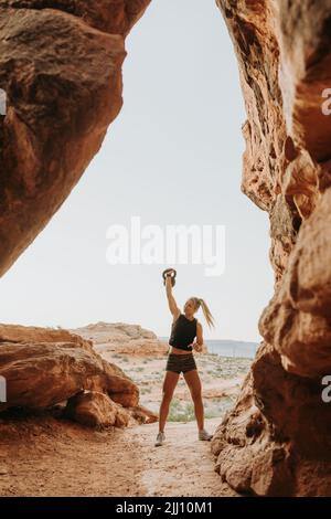 Junge Frau, die draußen im Wüstenland eine Kettlebell-Übung macht Stockfoto