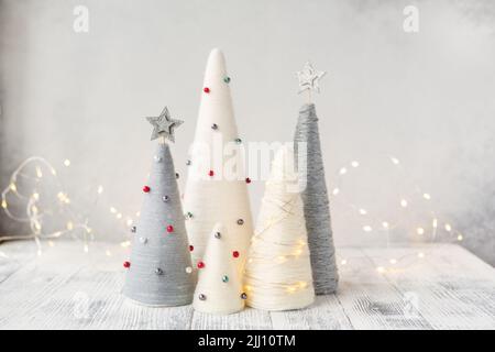 Handgefertigte Weihnachtsbäume. Garnumwickelte Kegelbäume. WEIHNACHTSGESCHENKE. DIY-Konzept Stockfoto