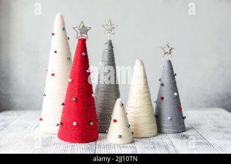 Handgefertigte Weihnachtsbäume. Garnumwickelte Kegelbäume. WEIHNACHTSGESCHENKE. DIY-Konzept Stockfoto