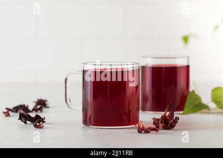 Kräutertee aus Hibiskusblüten in einer transparenten Tasse. Stockfoto