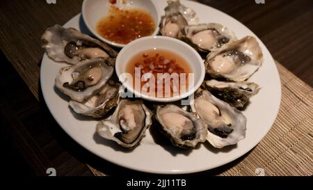 Teller mit frischen rohen Austern mit Vinaigrette und würziger Sauce Stockfoto