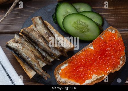 Nahaufnahme russischer Snack Lachskaviar, Sprotte Baltic. Low-Key, selektiver Fokus, Stillleben. Konzept der spät-Nacht-Essen, kleine Mitternachtssnack, Midnight Stockfoto