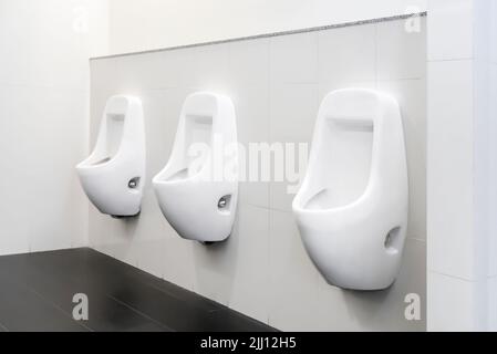 Öffentliche Toilette sauber, moderne weiße Fliesen, Urinal. Stockfoto