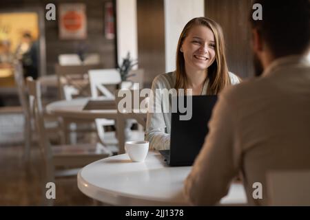 Junges Paar, das im Café am Laptop arbeitet. Ein hübscher junger Mann und eine attraktive Frau verbringen Zeit miteinander. Coworking und Freelance Konzept. Stockfoto