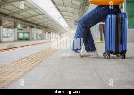 Frau, die auf der Tasche sitzt und am Bahnsteig im Skytrain-Bahnhof wartet. Stockfoto