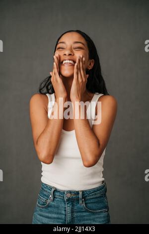 Afroamerikanische Frau, die ihr Gesicht mit den Händen reibt Stockfoto