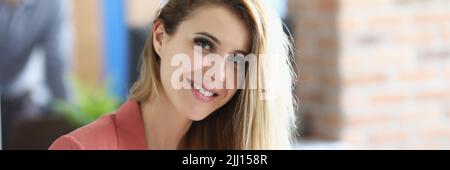 Attraktive blonde Dame sitzen in persönlichen Schrank halten Brille Stockfoto