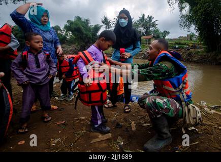 Garut, Indonesien. 22.. Juli 2022. Ein Soldat hilft einem Jungen, seine Rettungsweste nach einer Schlauchbootfahrt über den Cimanuk-Fluss in Garut, West-Java, Indonesien, am 22. Juli 2022 abzuziehen. Überschwemmungen und Überläufe haben eine Brücke über den Cimanuk-Fluss in der Region beschädigt. Quelle: Septianjar/Xinhua/Alamy Live News Stockfoto