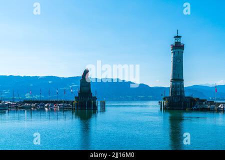 Deutschland, Lindau Island City Hafen Leuchtturm mit Blick auf österreich und bregenz Stadt am frühen Morgen mit blauem Himmel und Sonne im Sommer Stockfoto