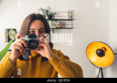 Junger geheimnisvoller langhaariger Kerl, der in seinem Zimmer fotografiert - Leidenschaft. Hochwertige Fotos Stockfoto