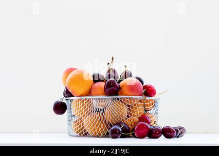 Süße Kirschen mit Aprikosen isoliert auf weißem Hintergrund Ausschnitt. Reife Beeren aus der Nähe. Stockfoto