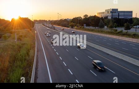Die Sonne geht über der Autobahn auf und der Verkehr am frühen Morgen Stockfoto