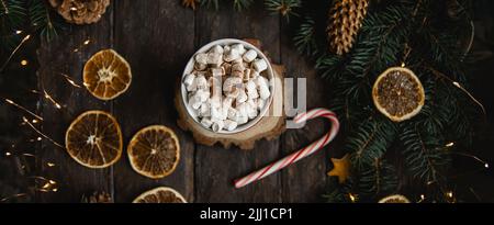 Weihnachten Hintergrund Zuckerrohr Zweige heiße Schokolade Getränke getrocknete Orangenscheiben auf dunklem Holzhintergrund. Urlaubskarte. Draufsicht flach liegend. Christus Stockfoto