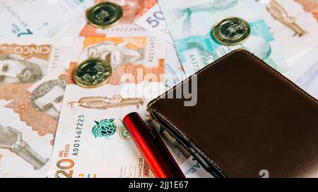 Ein kolumbianisches Geld in verschiedenen Stückelungen mit Münzen und Geldbörse. Geschäftskonzept Stockfoto