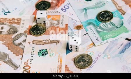 Ein kolumbianisches Geld in verschiedenen Stückelungen mit Münzen und Würfeln. Stockfoto