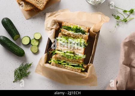 Hausgemachte englische Teegurken-Sandwiches mit Ricotta und Dill auf weißem Hintergrund. Nahaufnahme. Knusprige frische kalte Sommervorspeise. Stockfoto