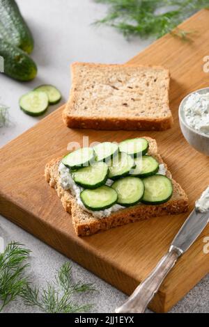 Zum Frühstück werden traditionelle englische Teegurken-Sandwiches mit Ricotta und Dill zubereitet. Nahaufnahme. Knusprige frische kalte Sommervorspeise. Stockfoto