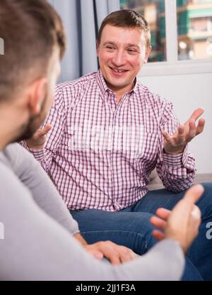 Guy lebhafte Diskussion mit Freund auf der Couch Stockfoto
