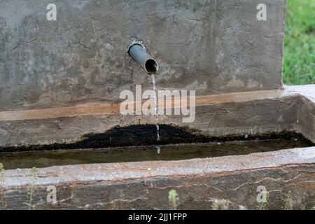 Selektive Fokusaufnahme aus der entgegengesetzten Ansicht des Springbrunnens in ländlicher Umgebung mit eiserner Spitze. Stockfoto