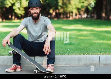 Gut gelaunter Skateboarder hat eine kurze Pause Stockfoto