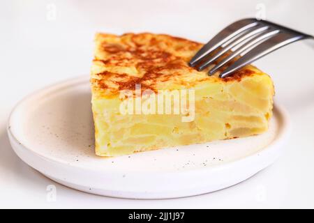 Nahaufnahme von Tortilla-Scheiben, spanisches Omelett mit Gabel. Traditioneller spanischer Tapa-Hintergrund. Stockfoto