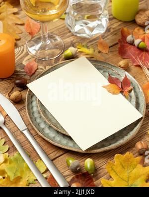 Rustikale Tischkulisse im Herbst mit leerer Karte zwischen bunten Blättern und Beeren, close up Vertikale Kartenmockup auf Holztisch, Platz kopieren. Ggf Stockfoto