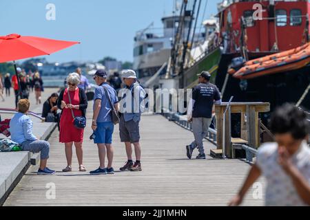 Touristen genießen sich auf der Promenade des Waterfront Trail im Hafen von Toronto neben dem festgetäuten Tall Ship Kajama, Ontario, Kanada. Stockfoto