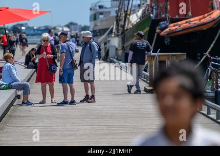 Touristen genießen sich auf der Promenade des Waterfront Trail im Hafen von Toronto neben dem festgetäuten Tall Ship Kajama, Ontario, Kanada. Stockfoto