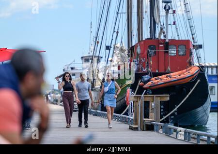 Touristen genießen sich auf der Promenade des Waterfront Trail im Hafen von Toronto neben dem festgetäuten Tall Ship Kajama, Ontario, Kanada. Stockfoto