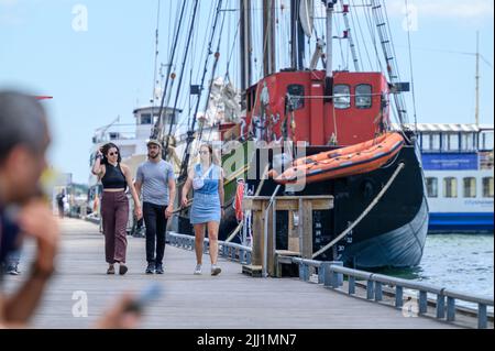 Touristen genießen sich auf der Promenade des Waterfront Trail im Hafen von Toronto neben dem festgetäuten Tall Ship Kajama, Ontario, Kanada. Stockfoto