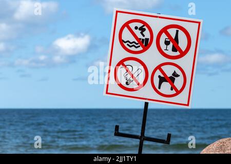 Auf einem weißen Banner an einer Küste sind Schilder für Strandregeln angebracht Stockfoto
