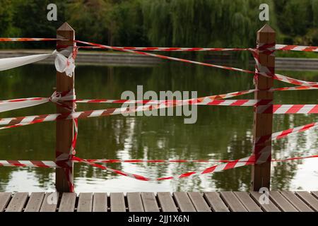 Holzdock am See mit rot-weißem Klebeband verschlossen Stockfoto