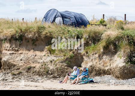 Garrettstown, Cork, Irland. 22.. Juni 2022. Deirdre und Michael O'Connell aus Kilkenny verbringen einen entspannten Tag bei strahlendem Sonnenschein und lesen am Strand von Garrettstown, Co. Cork, Irland. - Credit; David Creedon / Alamy Live News Stockfoto