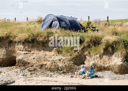 Garrettstown, Cork, Irland. 22.. Juni 2022. Deirdre und Michael O'Connell aus Kilkenny verbringen einen entspannten Tag bei strahlendem Sonnenschein und lesen am Strand von Garrettstown, Co. Cork, Irland. - Credit; David Creedon / Alamy Live News Stockfoto