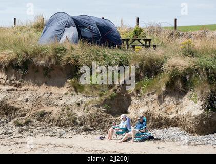 Garrettstown, Cork, Irland. 22.. Juni 2022. Deirdre und Michael O'Connell aus Kilkenny verbringen einen entspannten Tag bei strahlendem Sonnenschein und lesen am Strand von Garrettstown, Co. Cork, Irland. - Credit; David Creedon / Alamy Live News Stockfoto