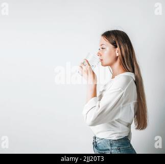 Asiatisches Mädchen mit lila Getränken Wasser aus einer Plastikflasche auf einem weißen, isolierten Hintergrund. Generation z. der Durstbegriff Stockfoto