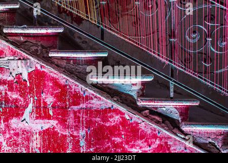 Rote Betontreppe mit dekorativem Geländer, Seitenansicht, Nahaufnahme Stockfoto