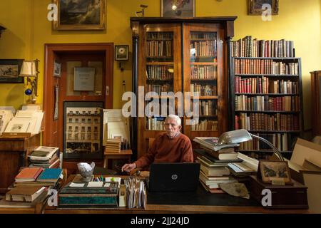 Reifer Mann sitzt in antiquarian Buchhandlung. Stockfoto