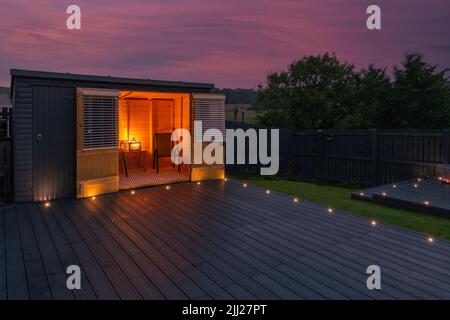 Aschgraue Verbundterrassen, die auf zwei Ebenen in einem Wohngarten mit Niederspannungs-Deckelbeleuchtung errichtet wurden. Gutes Bild für eine Landschaft Stockfoto