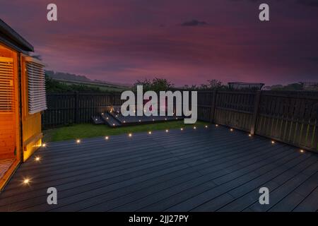 Aschgraue Verbundterrassen, die auf zwei Ebenen in einem Wohngarten mit Niederspannungs-Deckelbeleuchtung errichtet wurden. Gutes Bild für eine Landschaft Stockfoto