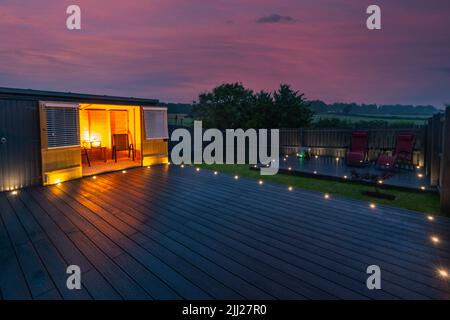 Aschgraue Verbundterrassen, die auf zwei Ebenen in einem Wohngarten mit Niederspannungs-Deckelbeleuchtung errichtet wurden. Gutes Bild für eine Landschaft Stockfoto