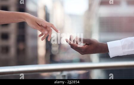 Wir könnten alle mit einer helfenden Hand auskommen. Zwei Menschen, die sich gegenseitig um die Hand greifen. Stockfoto