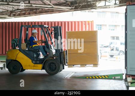 Gabelstapler werden in Frachtcontainer an Lagerhäusern, Häfen, Speditionen, Frachtlieferketten, Frachttransporten, Lagerindustrie, lo Stockfoto