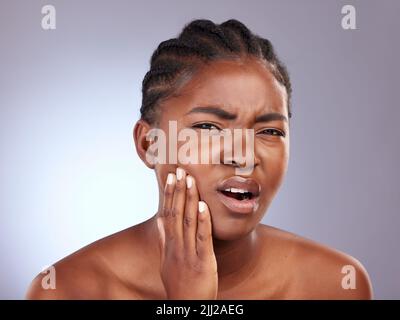 Diese Zahnschmerzen sind schrecklich. Studioaufnahme einer jungen Frau, die an Zahnschmerzen leidet. Stockfoto