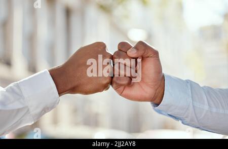 Ich motiviere Sie, Sie motivieren mich. Zwei unkenntliche Geschäftsleute, die sich gegenseitig eine Faust in der Stadt stoßen. Stockfoto