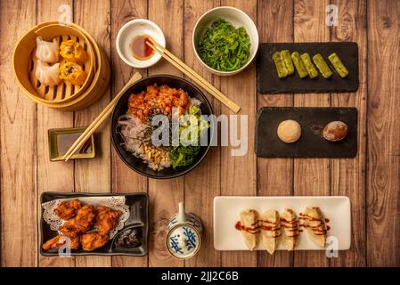 Asiatische Gerichte mit Bonbons aus grünem Tee, Gyozas, mochis und einer Schüssel mit Sojasauce und Wakame Stockfoto