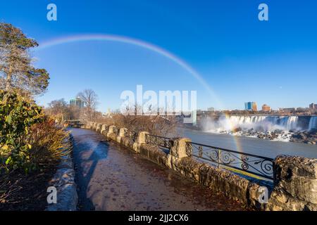 Niagara Falls, Ontario, Kanada - Dezember 13 2021 : Fallsview Trail an einem sonnigen Tag mit doppeltem Regenbogen. American Falls im Hintergrund. Stockfoto