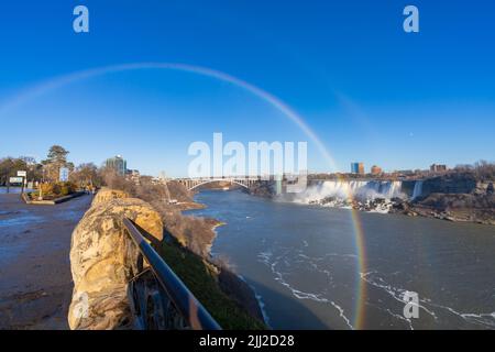 Niagara Falls, Ontario, Kanada - Dezember 13 2021 : Fallsview Trail an einem sonnigen Tag mit doppeltem Regenbogen. American Falls im Hintergrund. Stockfoto